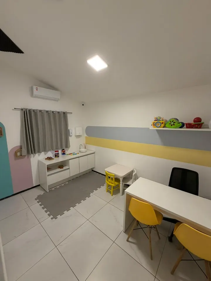 Sala de atendimento com bancada, mesinha infantil e brinquedos